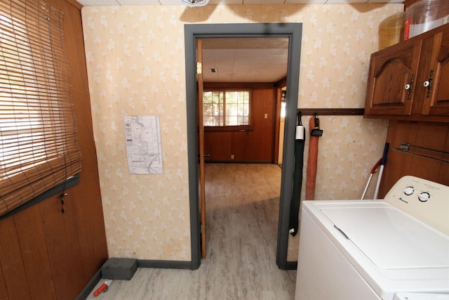 laundry area with light wood-type flooring, washer / clothes dryer, and cabinets