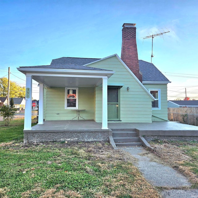 rear view of property featuring a porch and a lawn