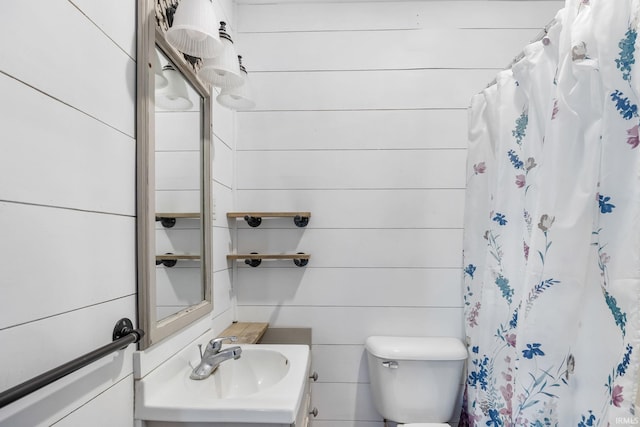 bathroom featuring vanity, curtained shower, toilet, and wood walls