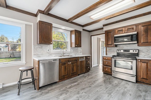 kitchen featuring tasteful backsplash, appliances with stainless steel finishes, sink, light wood-type flooring, and beam ceiling