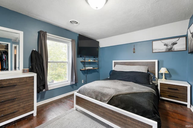 bedroom with a textured ceiling and dark hardwood / wood-style flooring