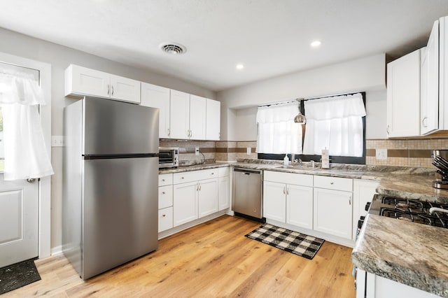 kitchen with light hardwood / wood-style floors, white cabinets, stainless steel appliances, and backsplash