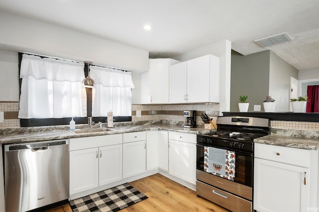 1316 S 19th St, New Castle, IN 47362 - kitchen with stainless steel appliances, a sink, backsplash, light wood-style flooring, and white cabinets