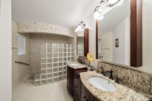 bathroom with vanity, backsplash, tile walls, and a shower