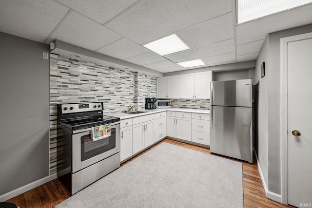 kitchen with decorative backsplash, appliances with stainless steel finishes, light hardwood / wood-style flooring, and white cabinetry