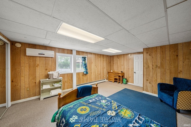 carpeted bedroom featuring a drop ceiling, wood walls, a baseboard heating unit, and an AC wall unit