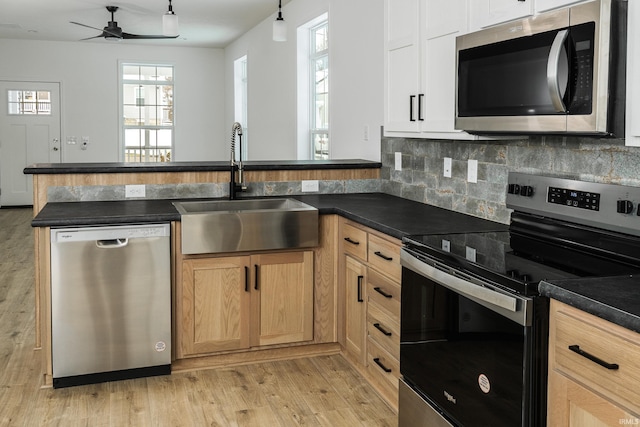 kitchen featuring a sink, appliances with stainless steel finishes, dark countertops, and ceiling fan