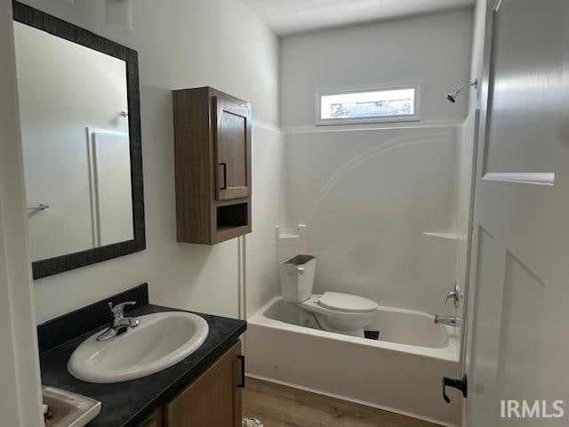 full bathroom with vanity, washtub / shower combination, hardwood / wood-style flooring, and toilet