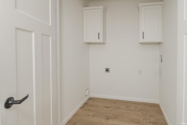 clothes washing area featuring cabinet space, electric dryer hookup, baseboards, and light wood-type flooring