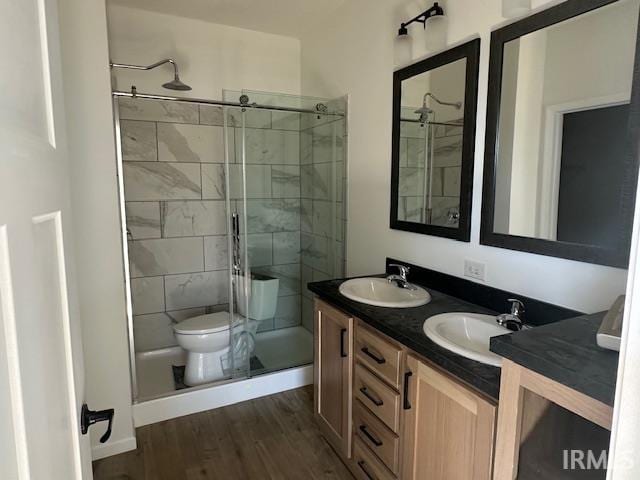 bathroom with toilet, hardwood / wood-style floors, vanity, and a shower with door