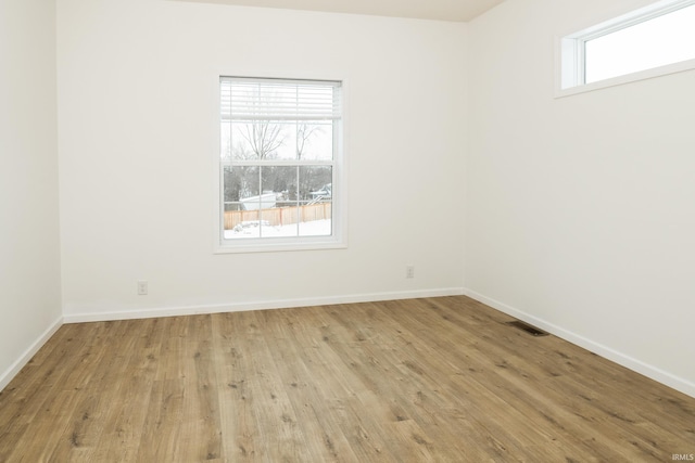unfurnished room with baseboards, wood finished floors, and visible vents