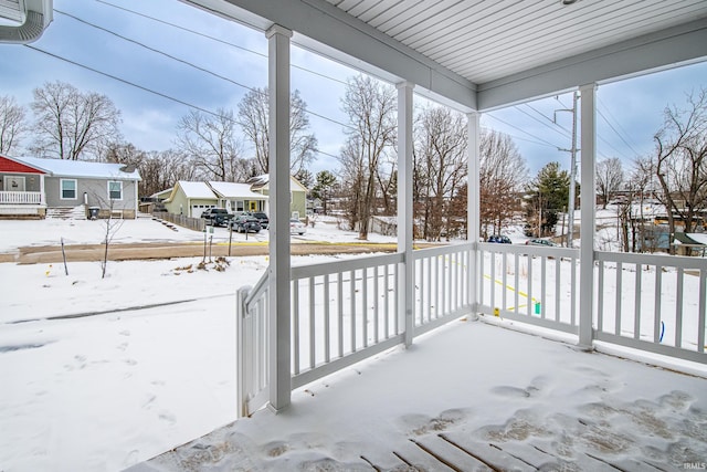snow covered patio with covered porch and a residential view