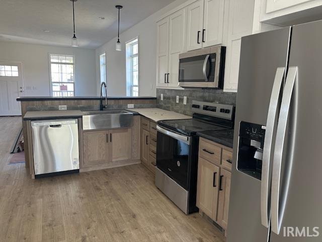 kitchen featuring kitchen peninsula, decorative light fixtures, stainless steel appliances, and sink