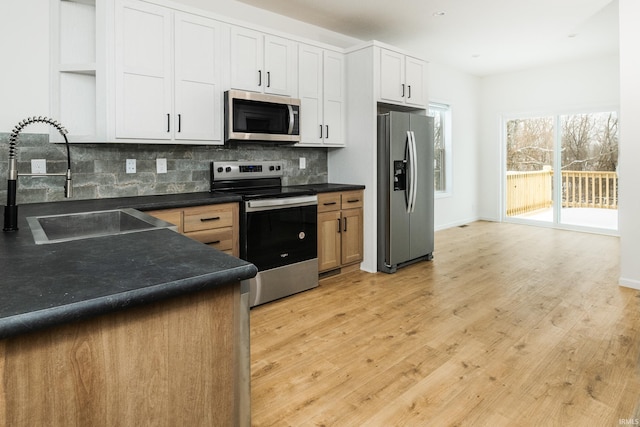 kitchen with a sink, backsplash, dark countertops, and stainless steel appliances