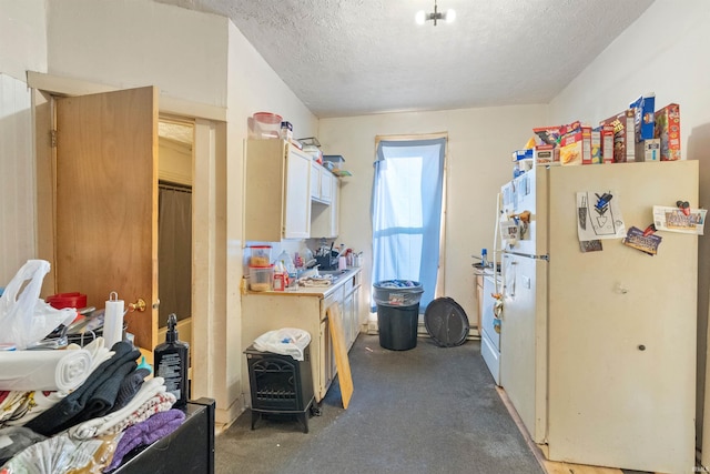 interior space with a textured ceiling, white fridge, and dark carpet