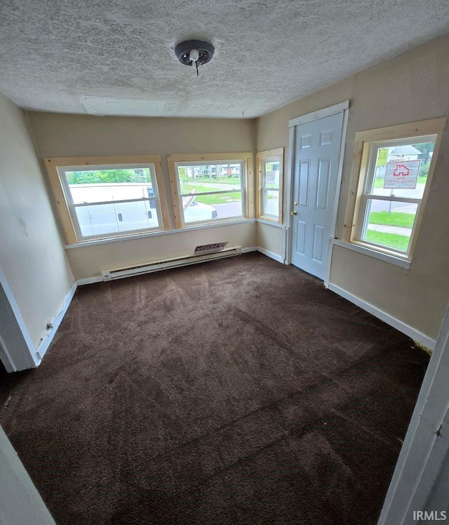 carpeted spare room featuring baseboard heating and a textured ceiling