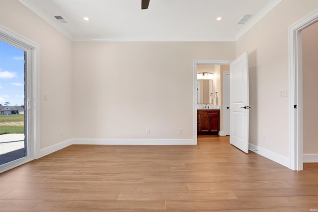 empty room featuring light wood-type flooring, crown molding, and plenty of natural light