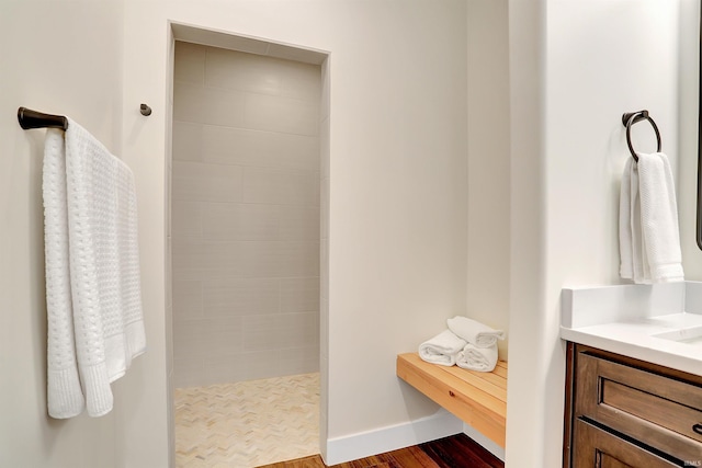 bathroom featuring a tile shower, hardwood / wood-style flooring, and vanity