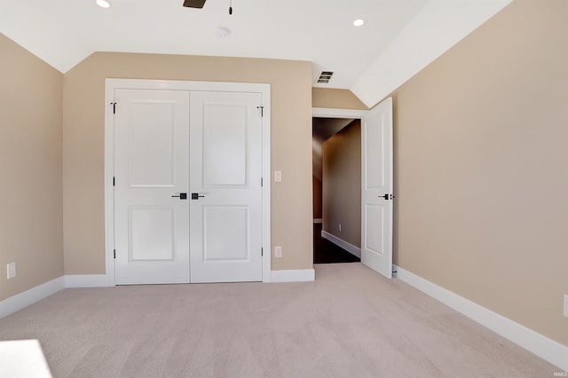 unfurnished bedroom featuring a closet, light carpet, lofted ceiling, and ceiling fan