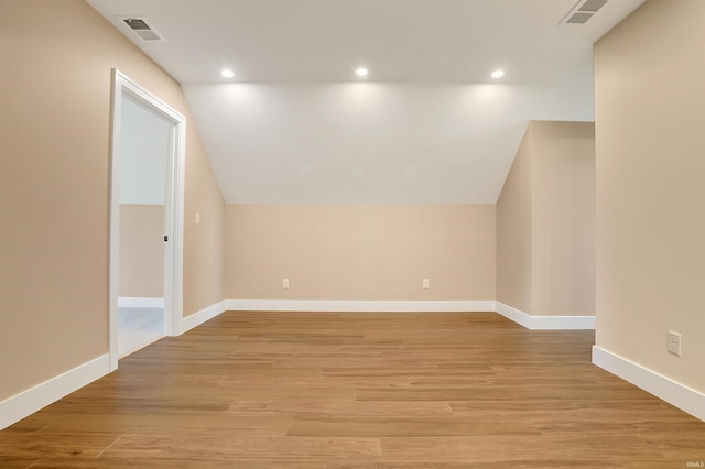 bonus room with light wood-type flooring and vaulted ceiling