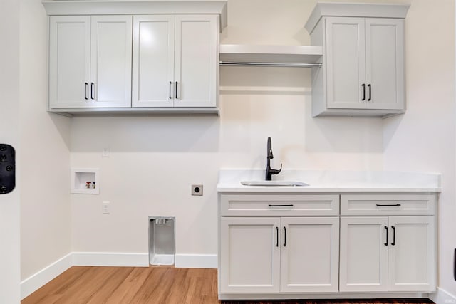 clothes washing area with washer hookup, hookup for an electric dryer, sink, light wood-type flooring, and cabinets