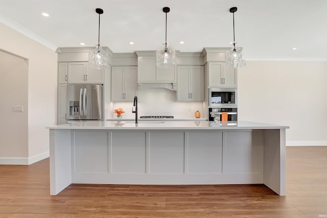 kitchen featuring a spacious island, light hardwood / wood-style flooring, decorative light fixtures, and stainless steel appliances