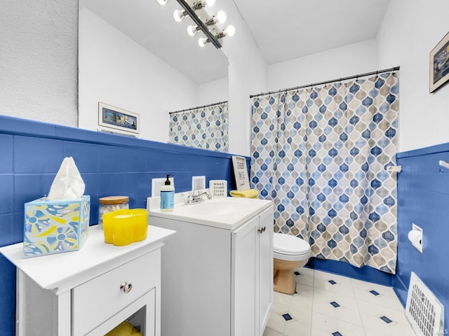 bathroom with vanity, curtained shower, toilet, and tile walls