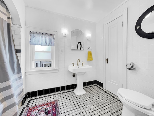 bathroom featuring toilet, tile patterned floors, and tile walls