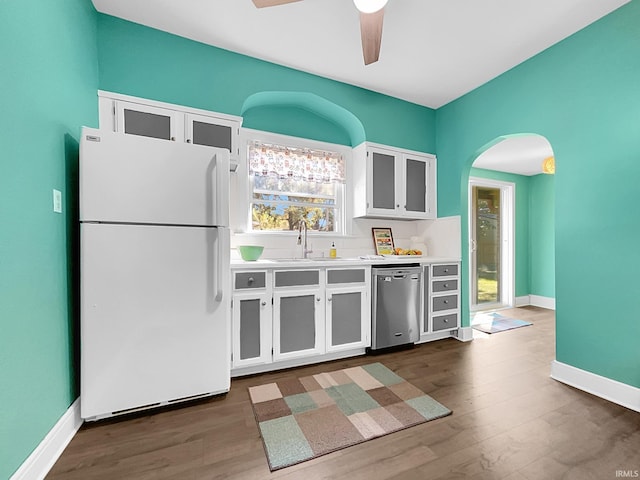 kitchen with dark wood-type flooring, sink, white refrigerator, stainless steel dishwasher, and white cabinets