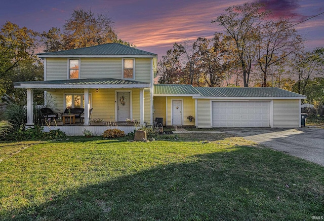 view of front of property with covered porch, a garage, and a lawn