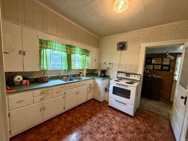 kitchen with hanging light fixtures, white cabinetry, white electric range, sink, and brick wall