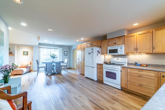 kitchen with light brown cabinetry, vaulted ceiling, light hardwood / wood-style floors, and white appliances