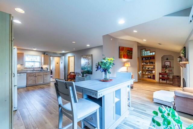 dining space with light hardwood / wood-style flooring, sink, and vaulted ceiling