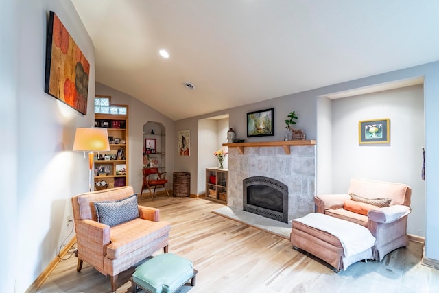 living room with light hardwood / wood-style flooring, lofted ceiling, and a tile fireplace