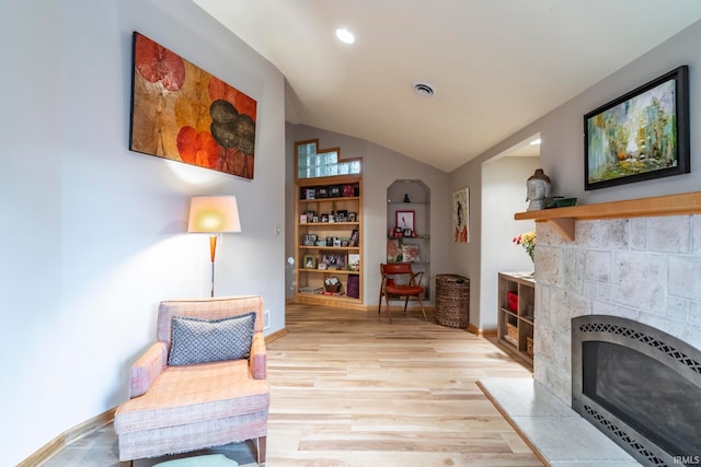 living area featuring vaulted ceiling, heating unit, and light wood-type flooring