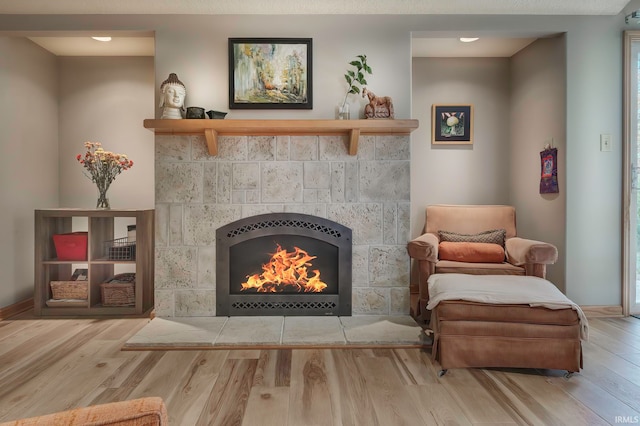 living area featuring a tiled fireplace and light hardwood / wood-style floors