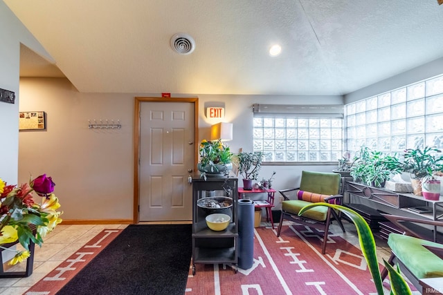 interior space with a textured ceiling, a healthy amount of sunlight, and light tile patterned floors