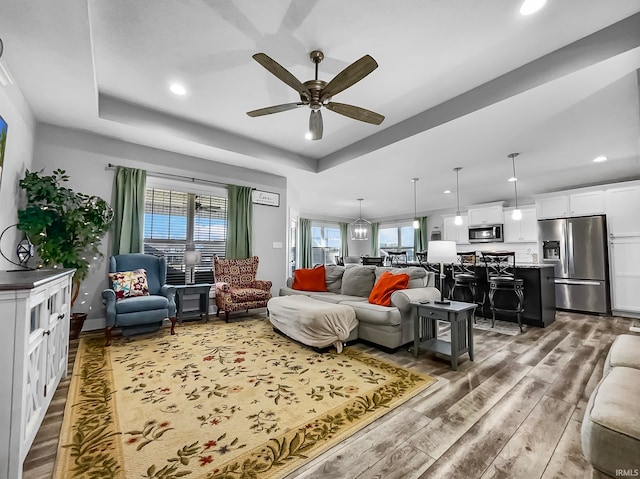 living room featuring hardwood / wood-style floors, a tray ceiling, and ceiling fan