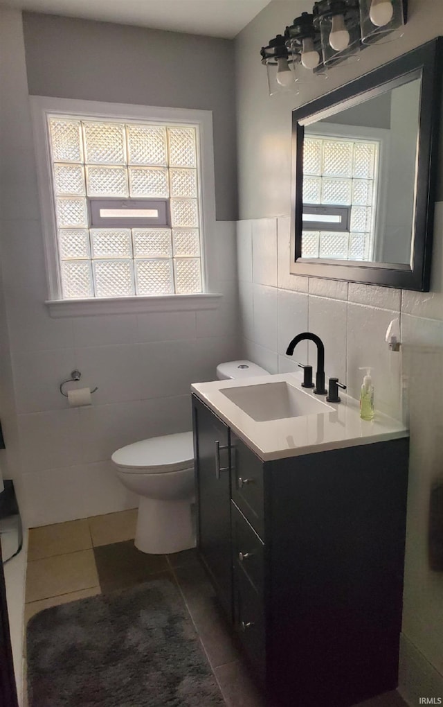 bathroom featuring tile walls, vanity, tile patterned flooring, and toilet