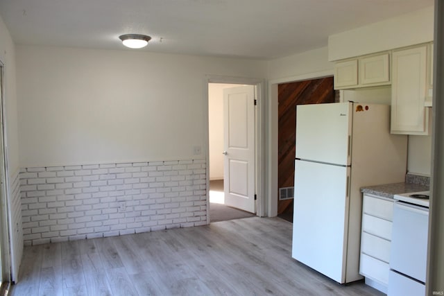 kitchen with white appliances and light hardwood / wood-style floors