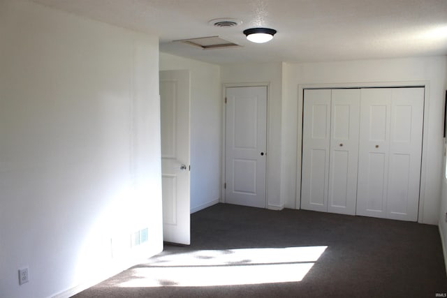 unfurnished bedroom featuring a closet and dark carpet