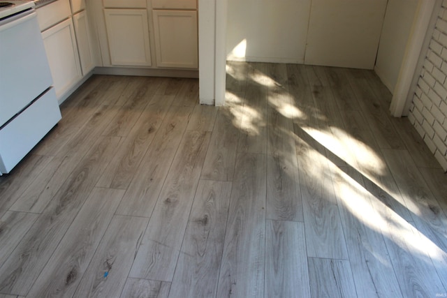 details with stove, white cabinetry, and light wood-type flooring