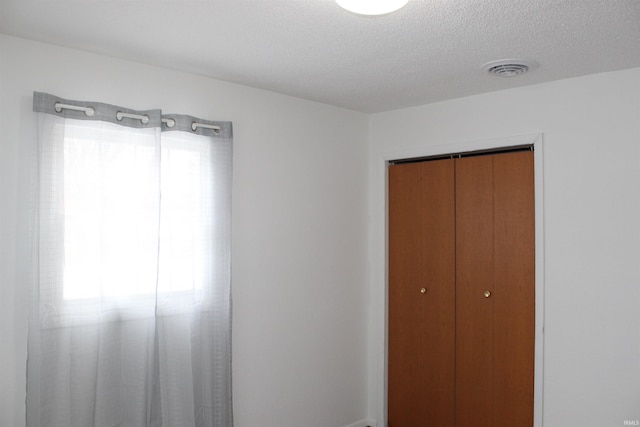 unfurnished bedroom featuring a textured ceiling and a closet