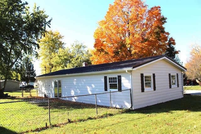 308 Clyde Ave, Angola, IN 46703 - view of home's exterior featuring a lawn, fence, metal roof, and a chimney