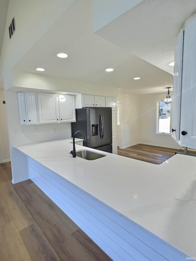 kitchen with kitchen peninsula, white cabinets, hardwood / wood-style flooring, stainless steel refrigerator with ice dispenser, and sink