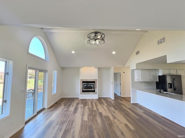 unfurnished living room featuring high vaulted ceiling, hardwood / wood-style flooring, and sink