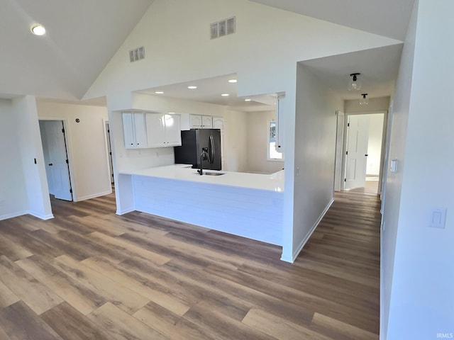 kitchen with kitchen peninsula, white cabinetry, wood-type flooring, stainless steel refrigerator with ice dispenser, and sink