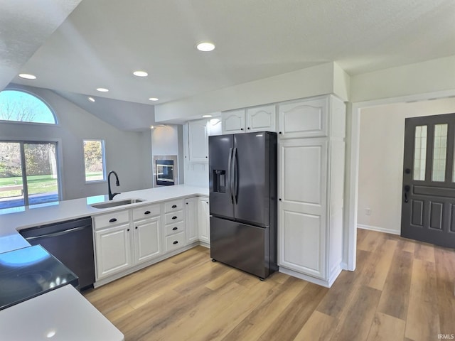 kitchen featuring sink, kitchen peninsula, white cabinetry, fridge with ice dispenser, and light hardwood / wood-style flooring