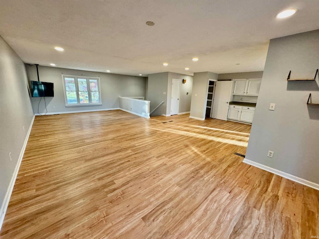 unfurnished living room featuring recessed lighting, baseboards, and light wood finished floors