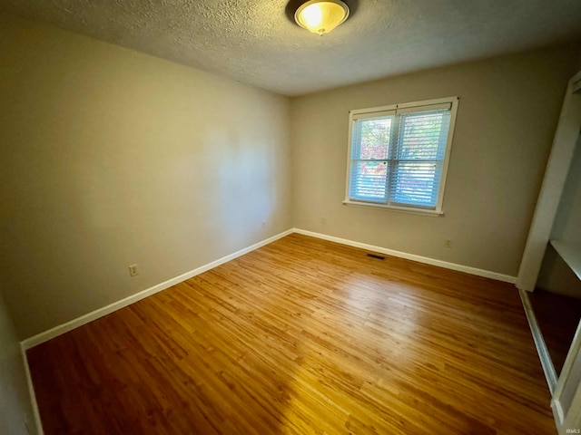 spare room with hardwood / wood-style floors and a textured ceiling